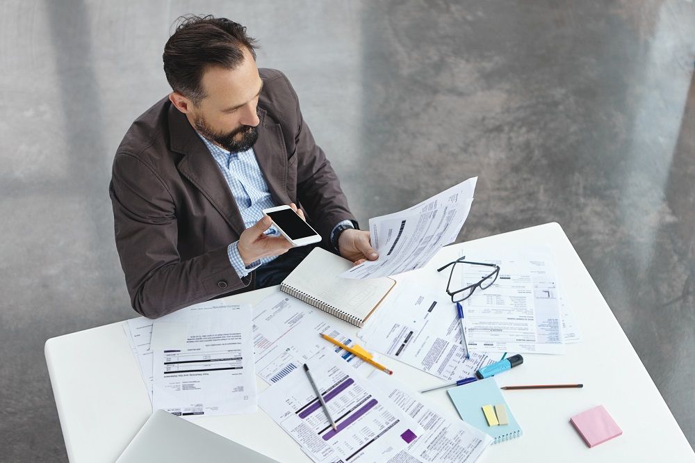 Verslininkas nagrinėja finansinius dokumentus prie darbo stalo